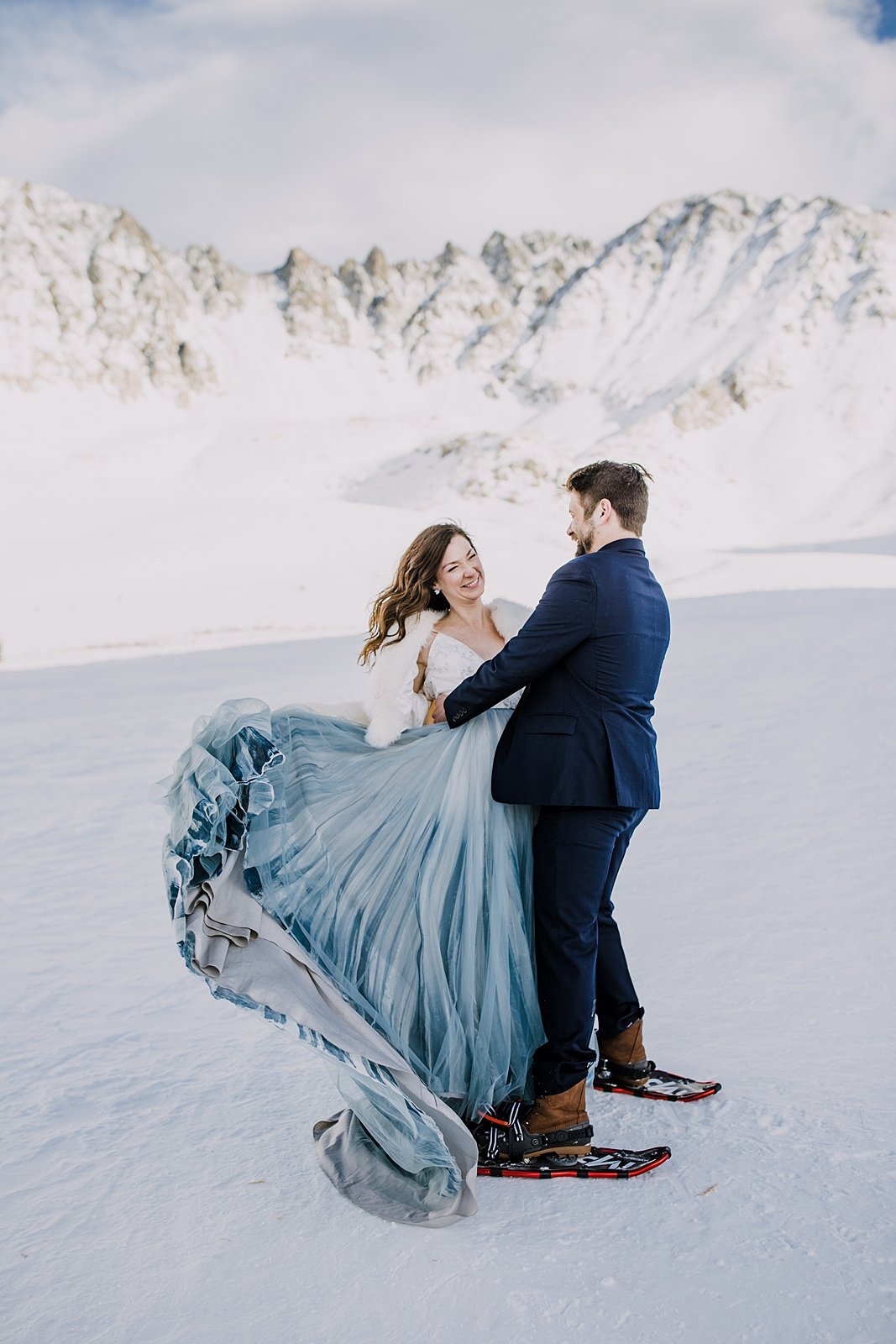 Bride and groom first dance in the snow, winter mountain elopement, yukon charlies womens snowshoes, colorado cabin wedding, bride swishing skirt, groom spinning bride