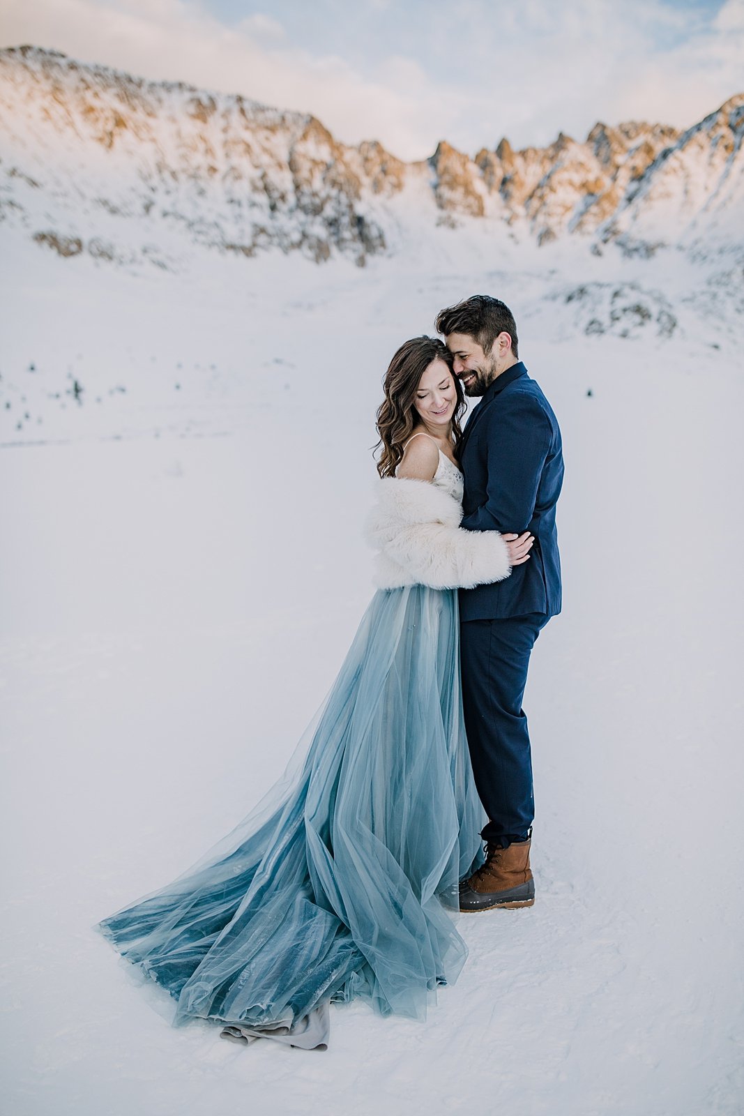 bride and groom embracing in the snow, snowy walk, winter elopement hiking boots, winter wedding hiking boots, winter alpenglow in mayflower gulch, sunset in mayflower gulch