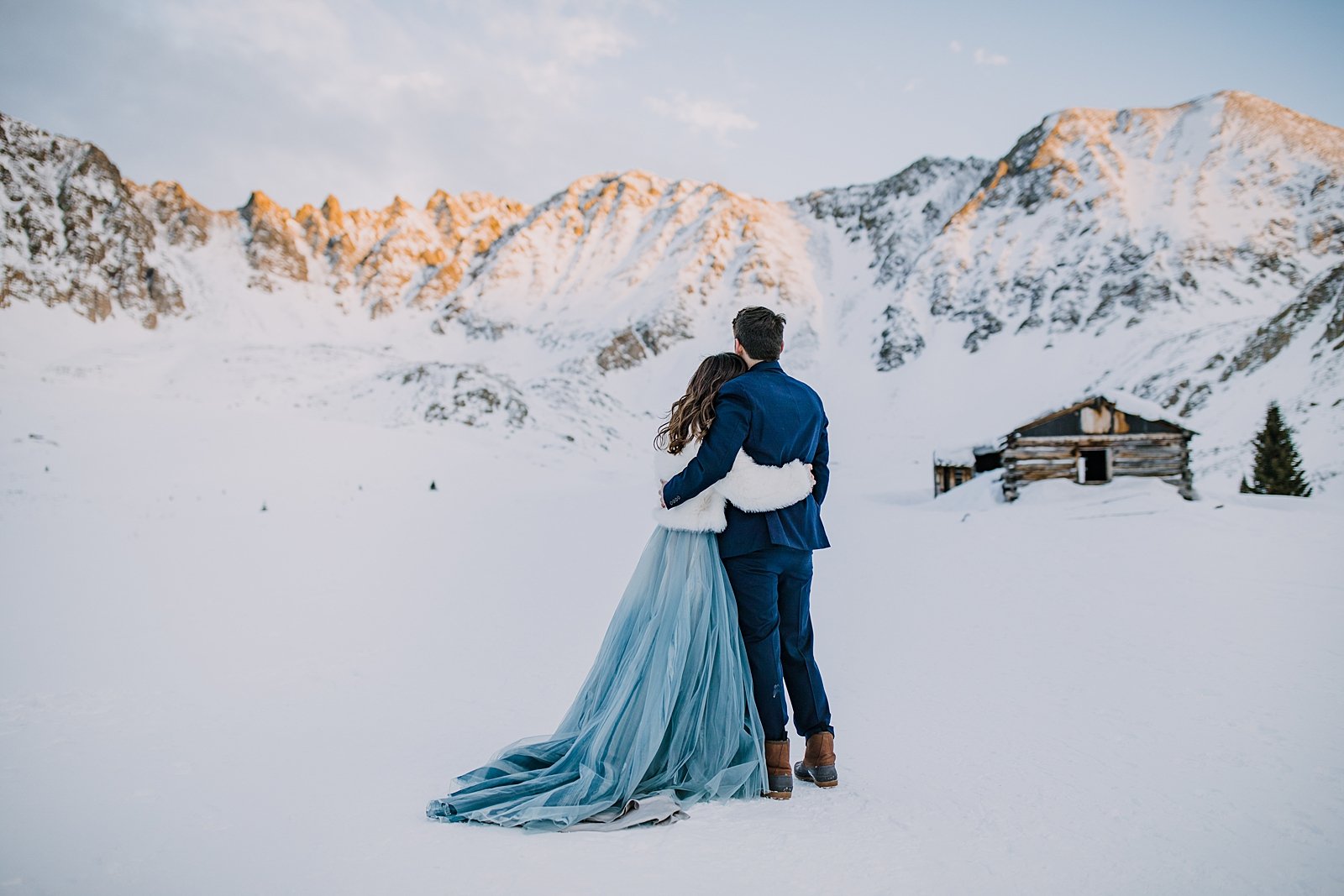 bride and groom watching sunset over mountain peaks, mountain alpenglow wedding, mountain alpenglow elopement, winter alpenglow elopement, winter mountain alpenglow in leadville