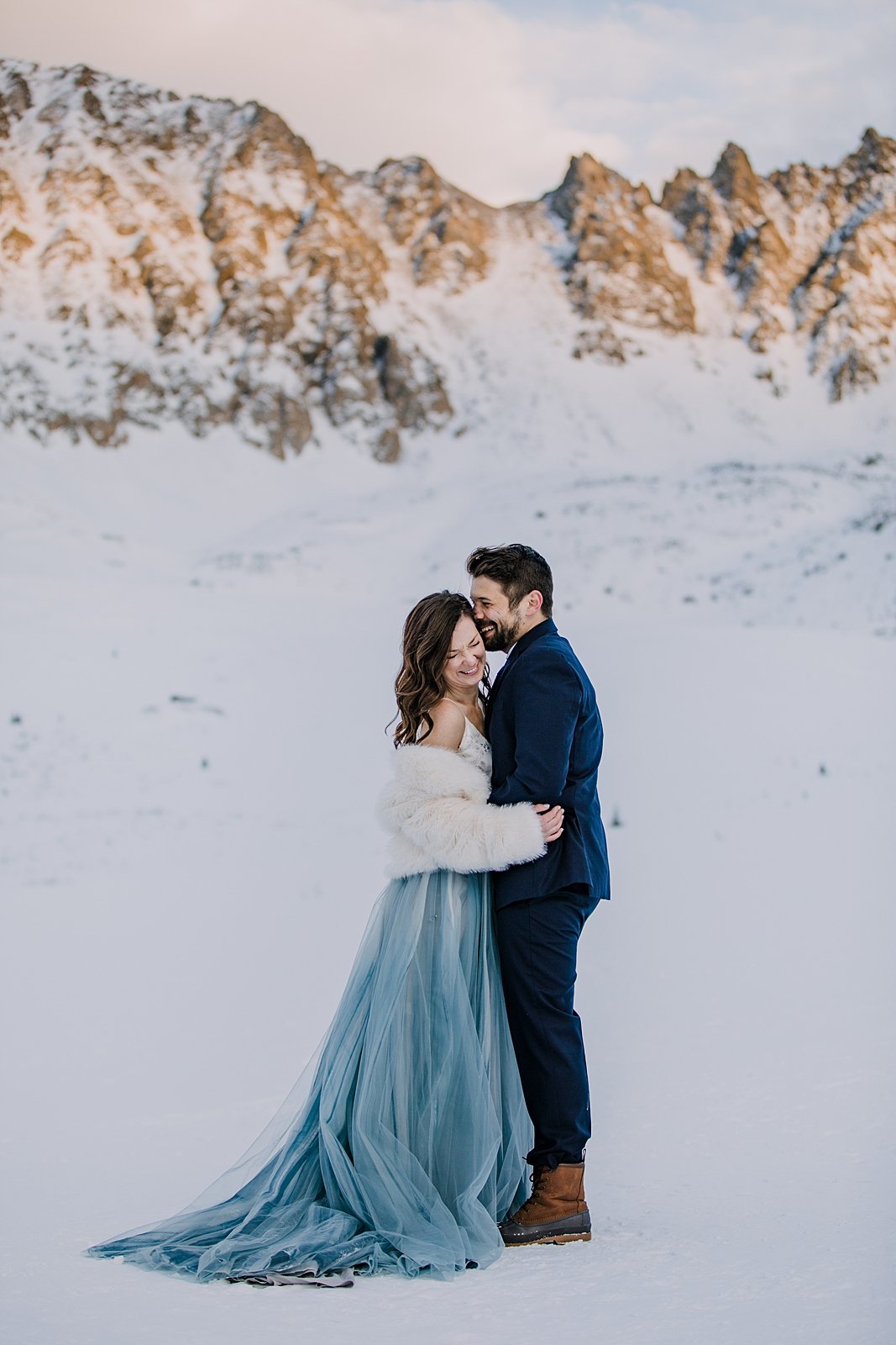 bride and groom embracing in the snow, snowy walk, winter elopement hiking boots, winter wedding hiking boots, winter alpenglow in mayflower gulch, sunset in mayflower gulch