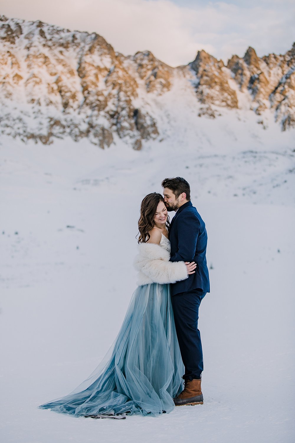 bride and groom embracing in the snow, snowy walk, winter elopement hiking boots, winter wedding hiking boots, winter alpenglow in mayflower gulch, sunset in mayflower gulch