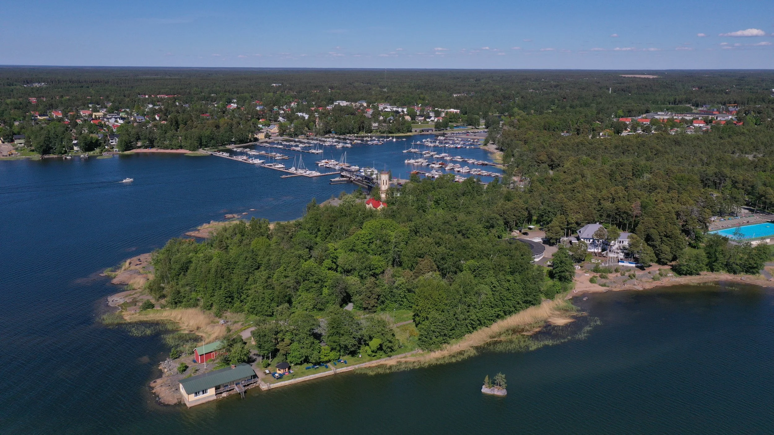 A floating concrete island planted with pines, juniper, hemlock and coastal plants, part of a site-specific environmental artwork by Raimo Saarinen in Otanlahti, Rauma.