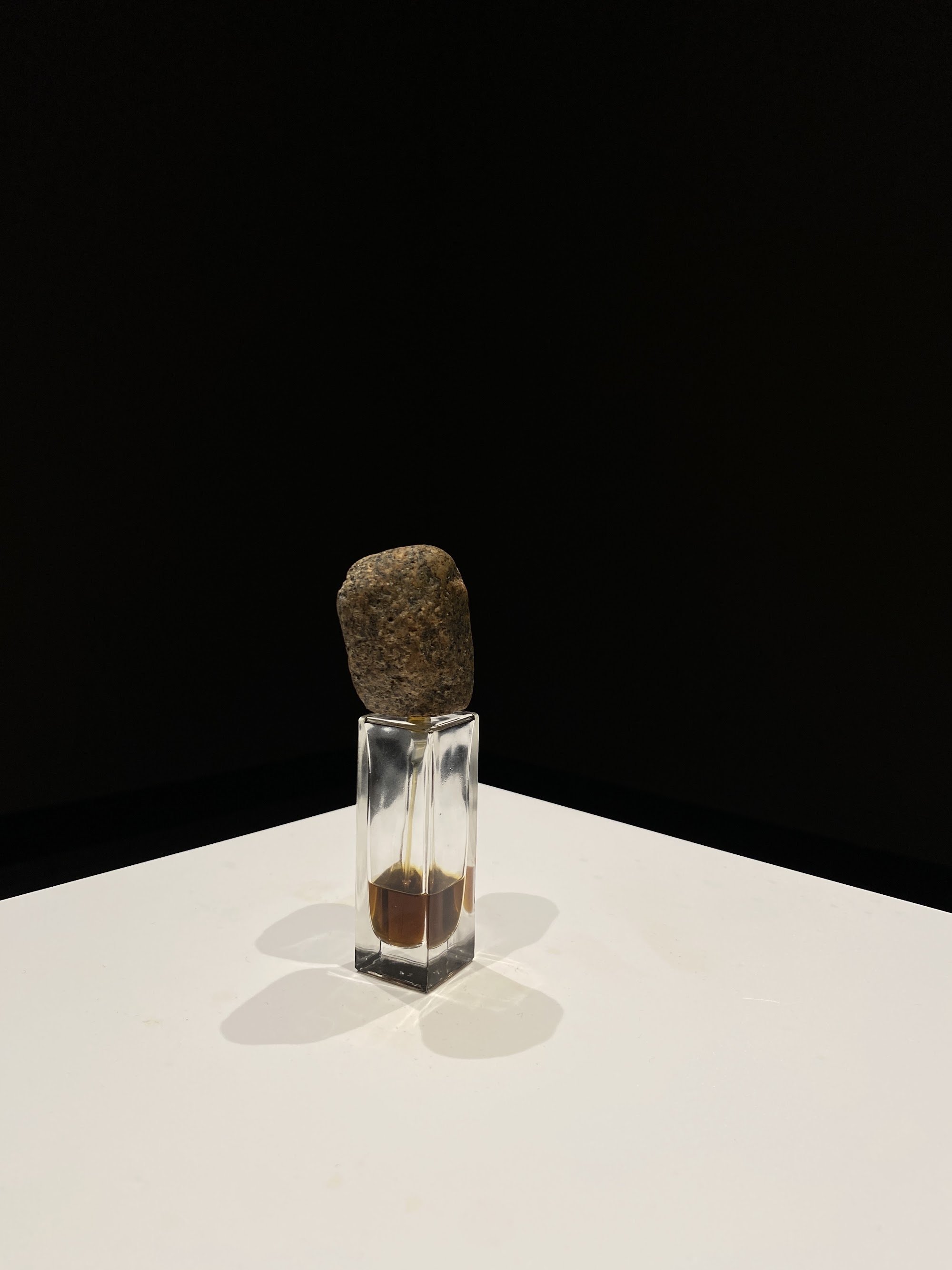 Eau de Terre: a small perfume bottle topped with a stone, on a white surface