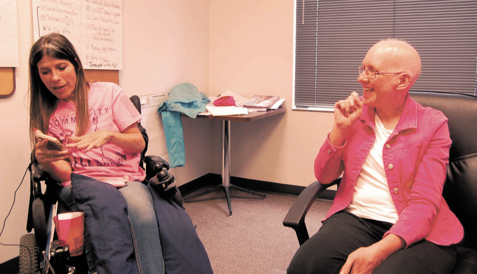Dawn Russell (left) and Dawn Howard (right) laugh as they listen to a song by fellow ADAPT activist Kalyn Heffernan’s band, Wheelchair Sports Camp. Credit: Erin Coleman