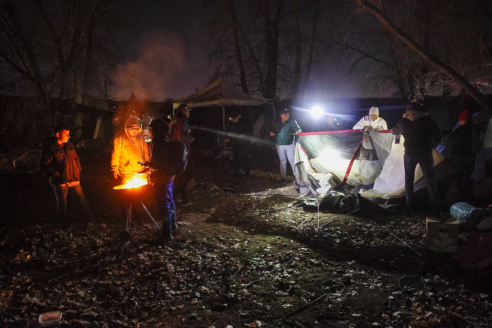  Volunteers and mew immigrants move a camp late into the night before a sweep. Credit: Giles Clasen 