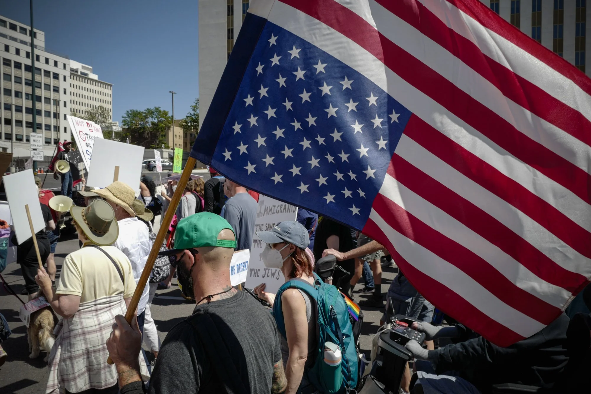 A large American flag is carried upside down as the crowd marches through downtown Denver