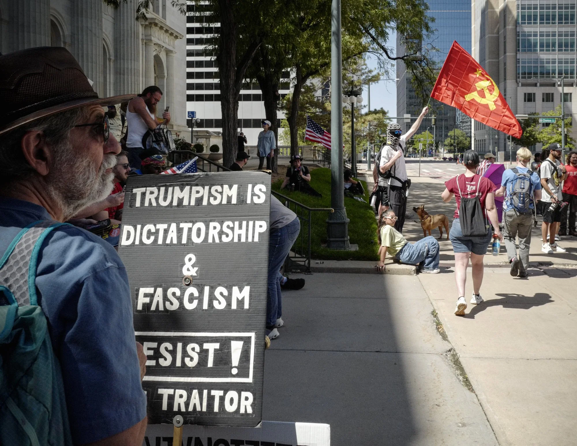 During a brief moment in the march, a protester stands in front of a sign reading "TRUMPISM IS DICTATORSHIP & FASCISM."