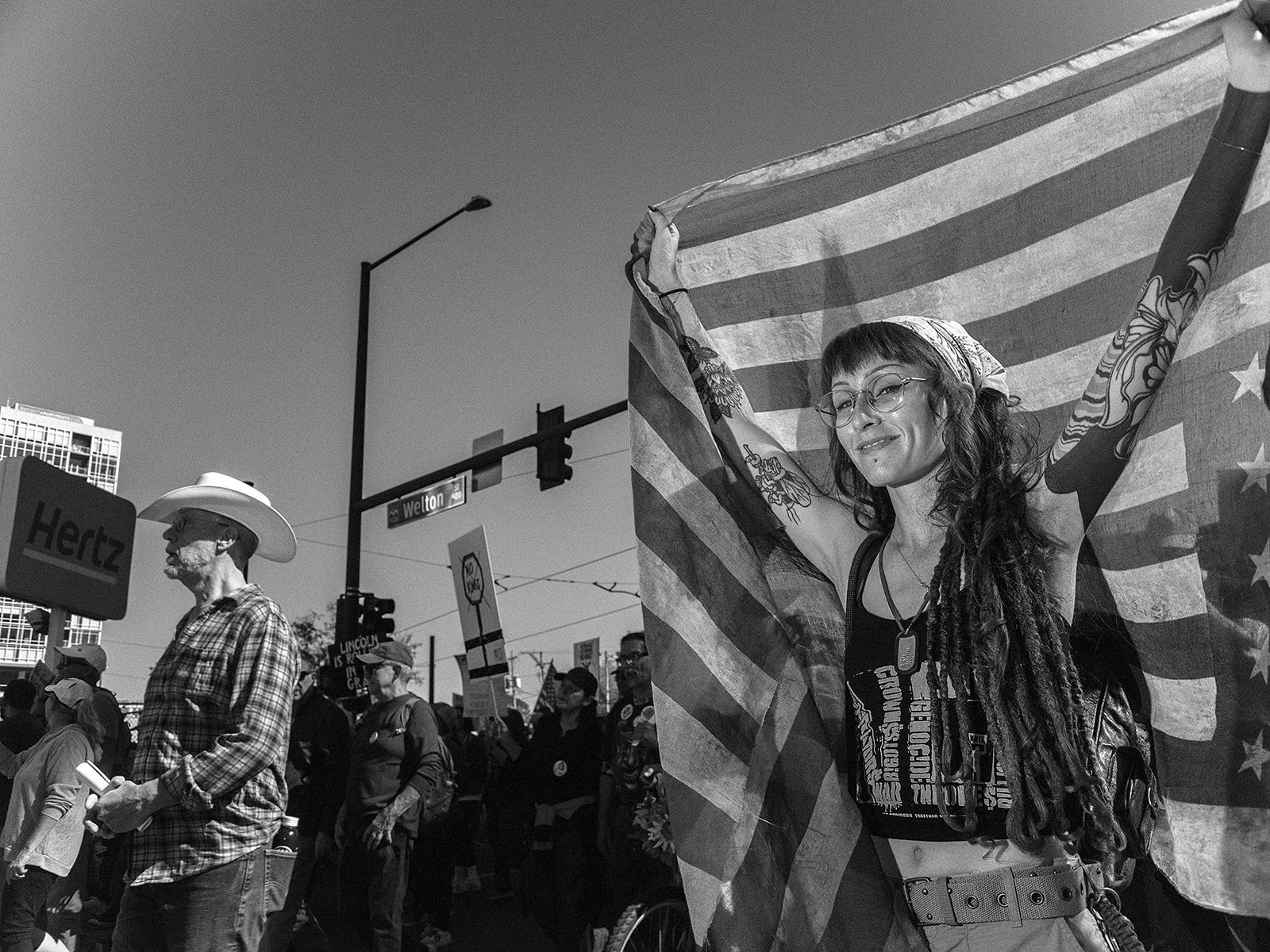 A participant drapes an American flag across raised arms while joining the No Kings march in downtown Denver on Saturday, Oct. 17, 2026. Photo by Jeff Tidwell for the Denver Voice.