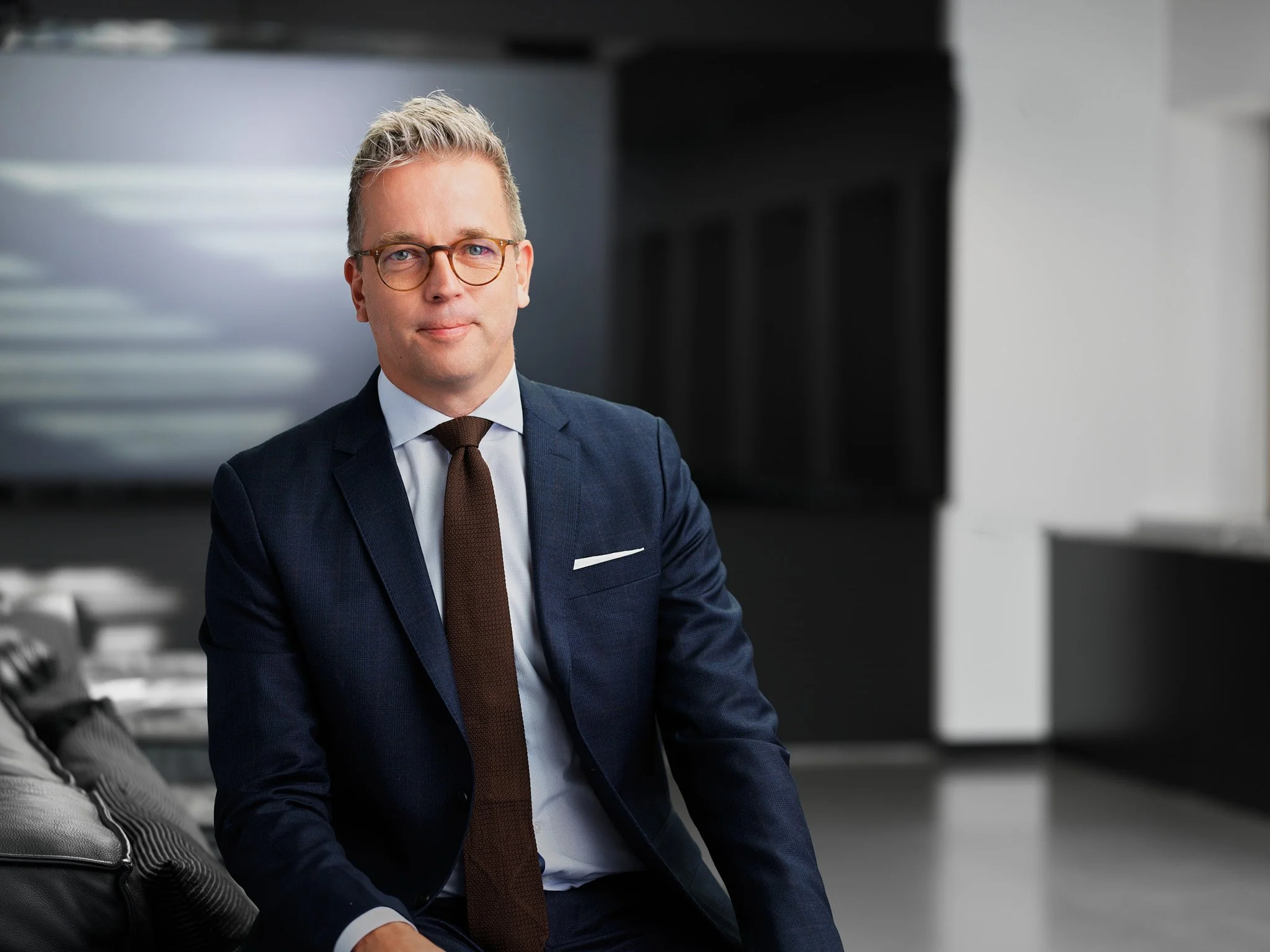 Johan Roman tummassa puvussa ja solmiossa Boreniuksen valoisassa toimistoympäristössä, taustalla avautuvat ikkunat ja moderni juristitoimisto.