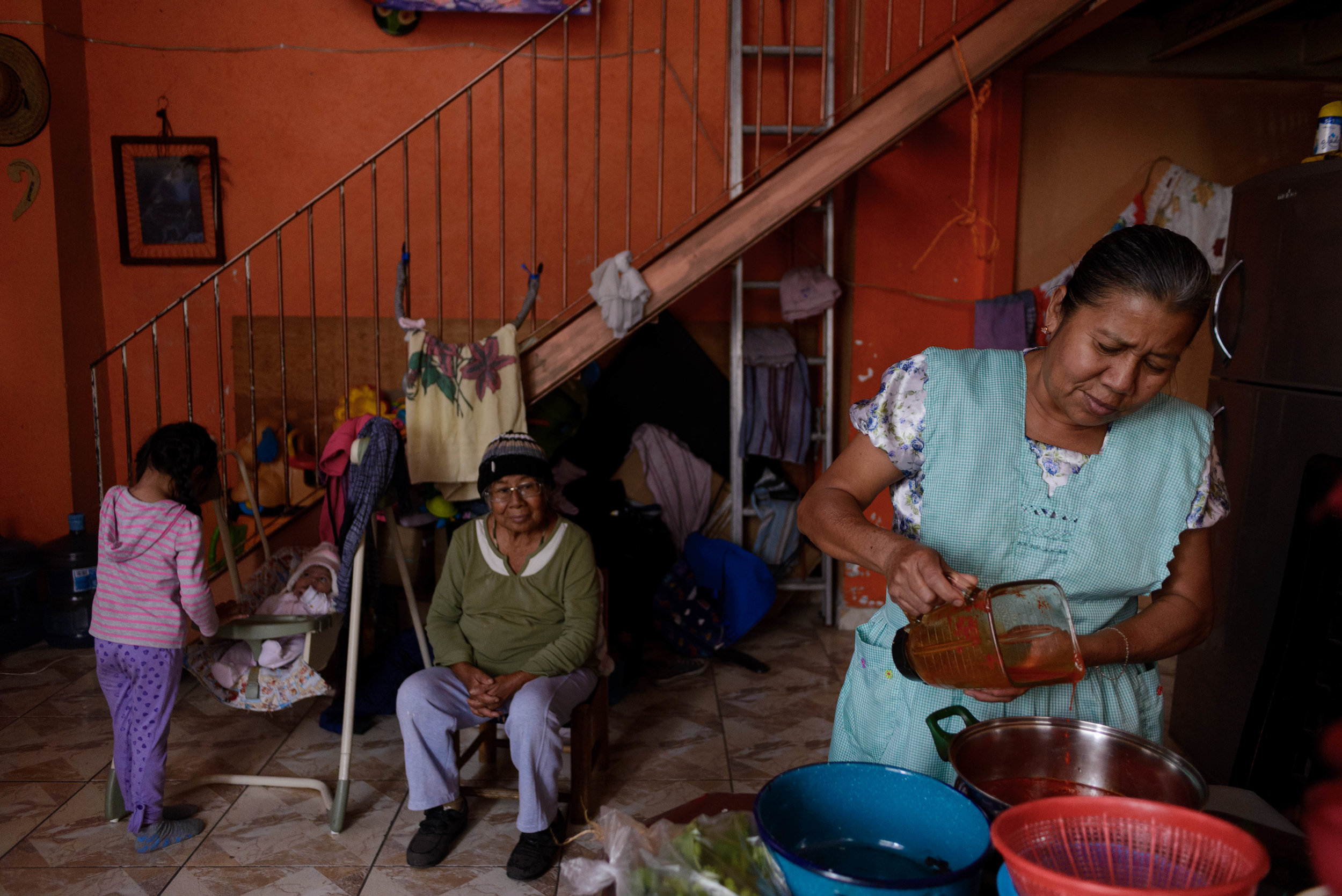  Hermenegilda prepares lunch for her family while 3 year old Merliza plays with her younger cousin and great-grandmother Agustina looks on at the scene. 