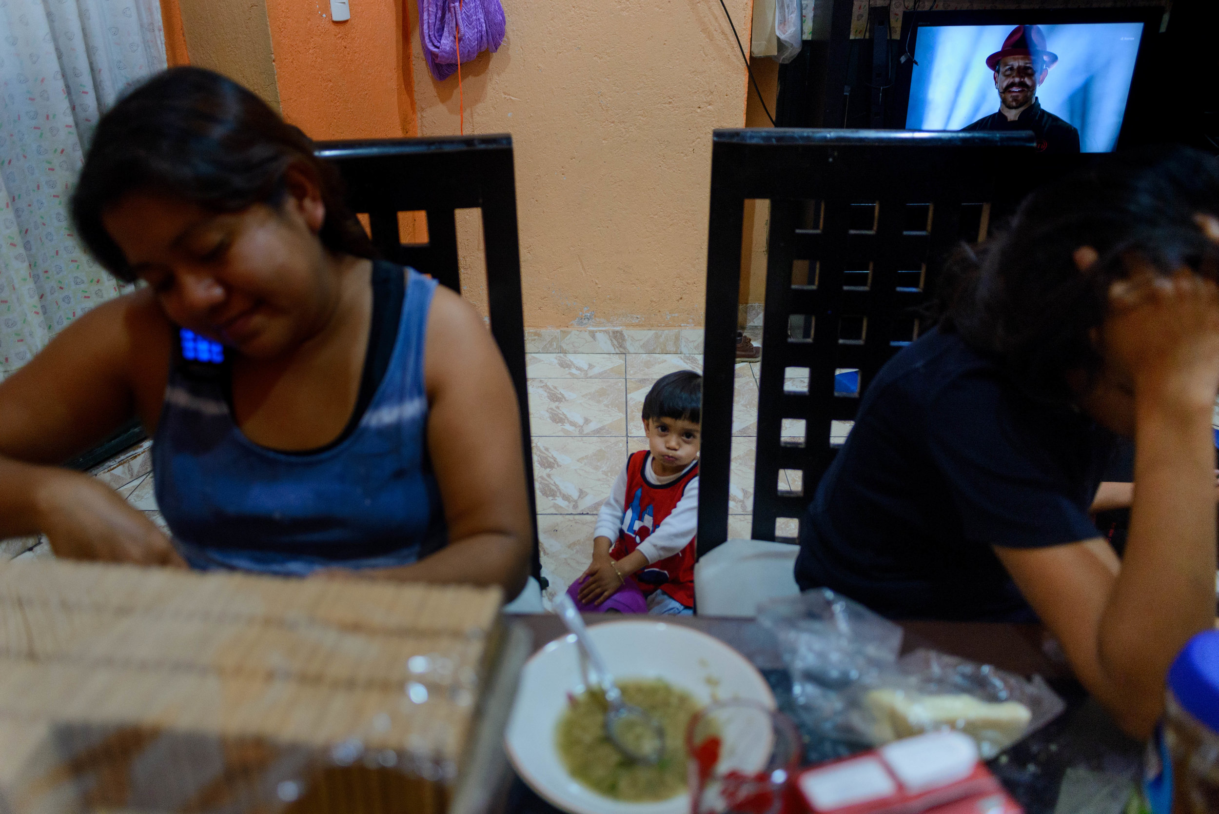  Jael looks at the camera while his mother speaks to his father on the phone one evening during dinner. 