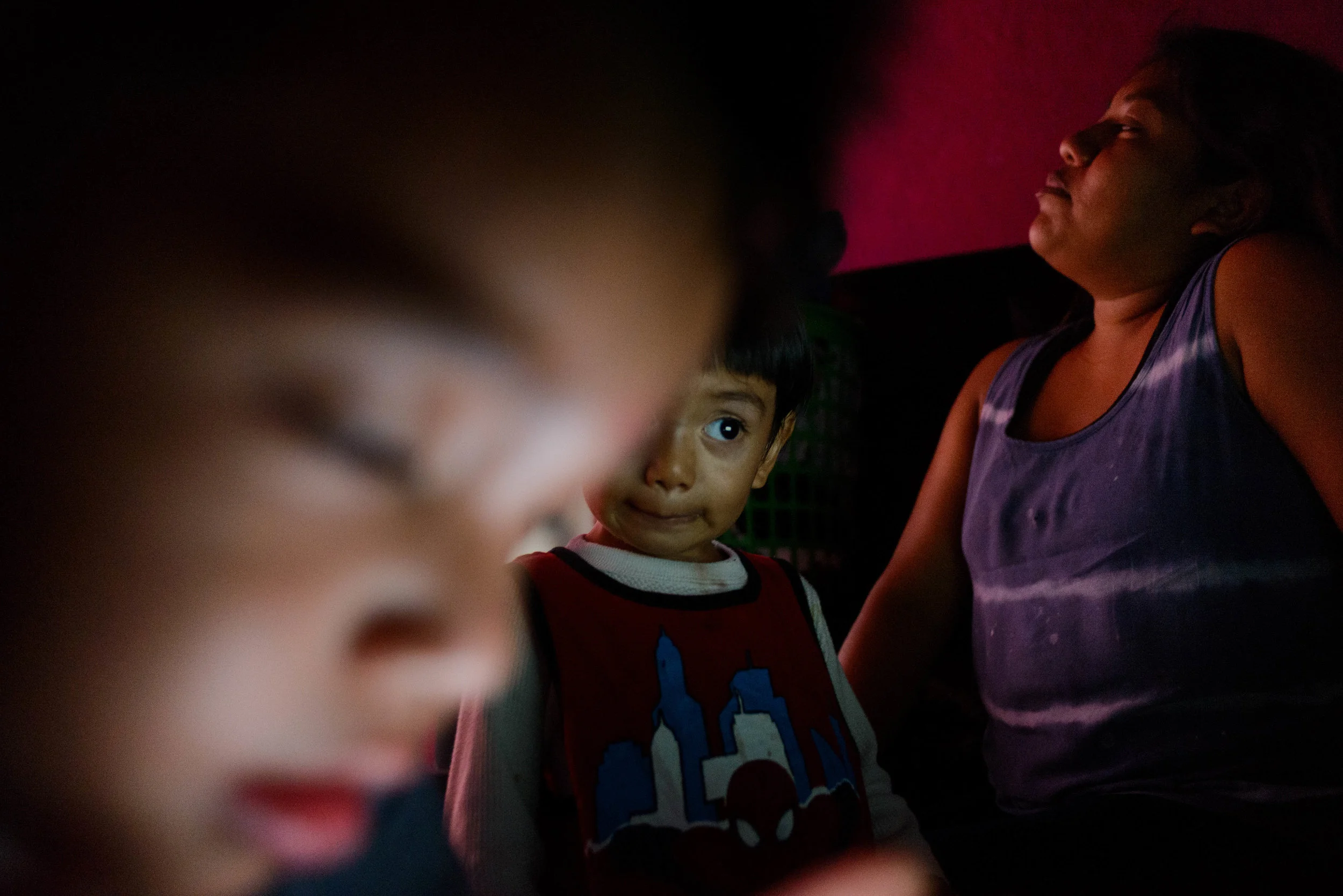 Josefina relaxes while her son and nephew entertain themselves with music videos on a laptop.