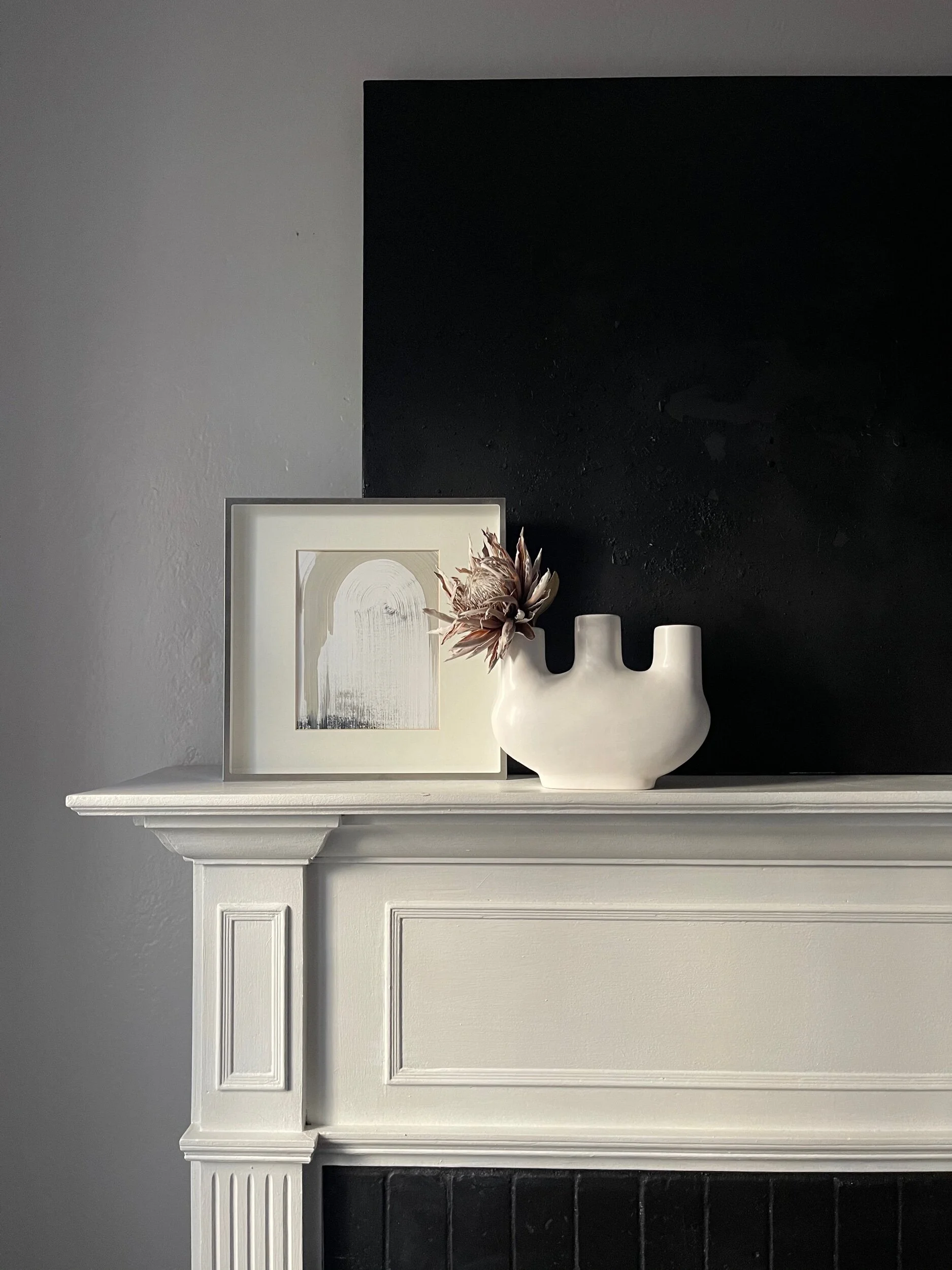 matte white abstract vase styled with artwork on mantle