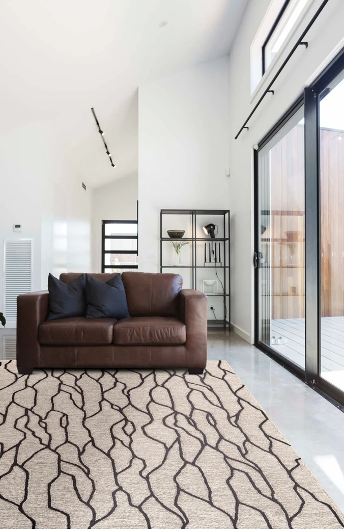 Leather Sofa in Living Room with Rectangular Modern Taupe Wool Rug Black Abstract Lines