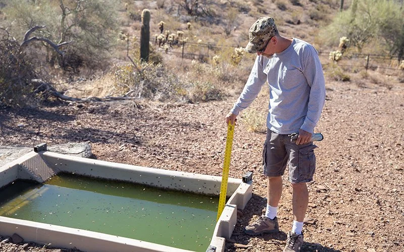 Jed Nitso uses a yardstick to measure a catchment's water level. Most of Arizona's catchments depend on patrolling Arizona Game &amp; Fish rangers and wildlife managers to monitor them. (Photo by Nick Serpa/Cronkite News)