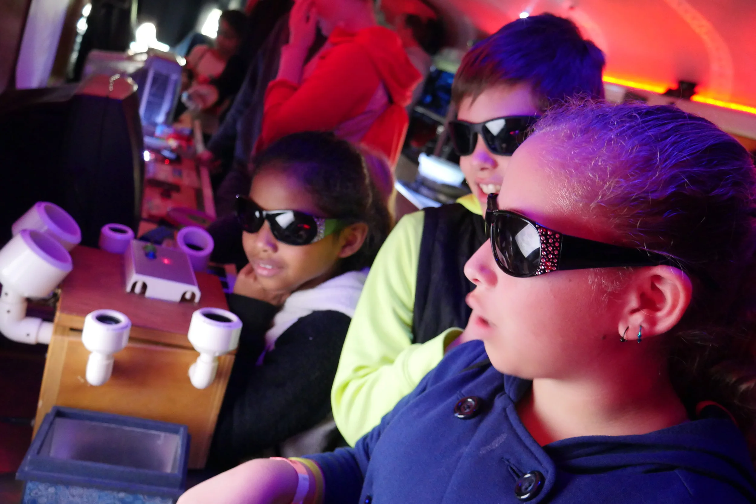 Inside the Physics Bus, a group of children put on special glasses and watch a movie through a warped television display. (Nicholas Serpa/DD)