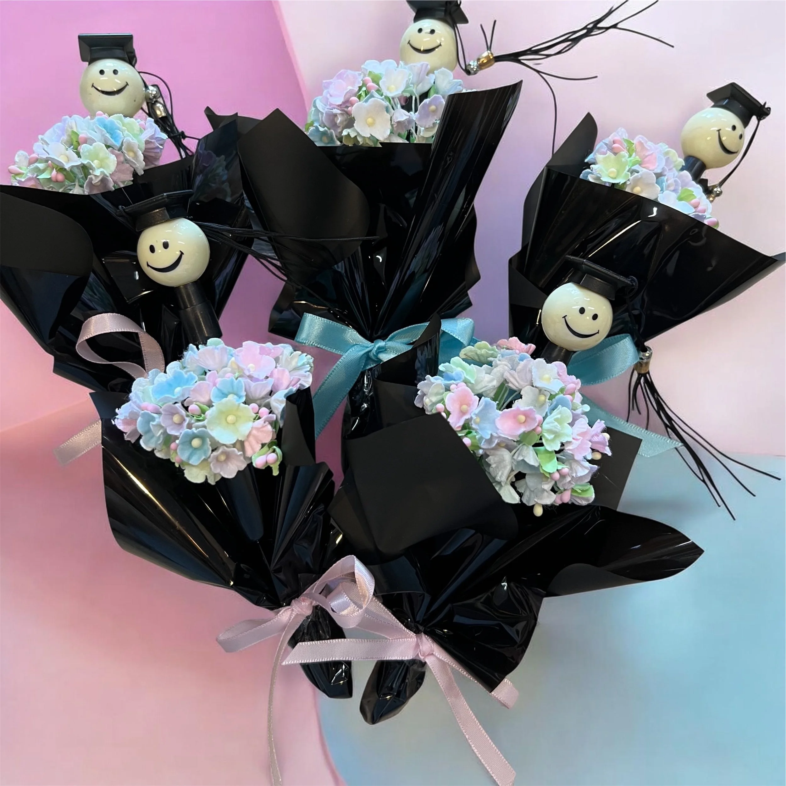 Small pastel graduation flower posy with smiley-face graduation cap pen, wrapped with a bow