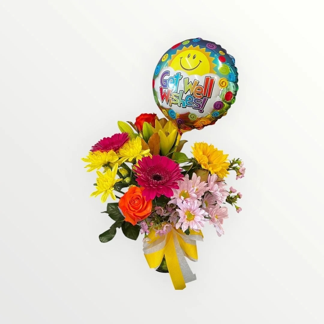 fresh bright flower posy  of seasonal flowers in a glass jar with a get well soon balloon