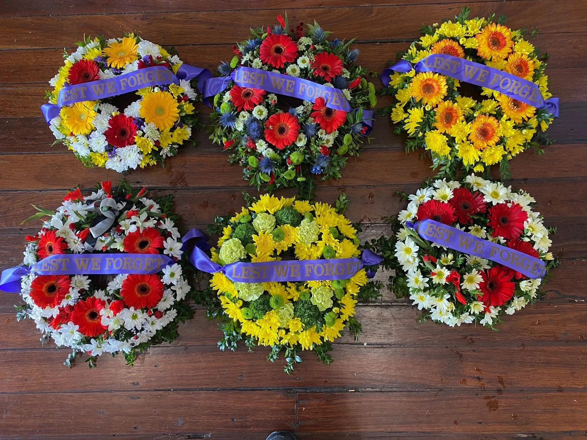 A collection of fresh flower wreaths with lest we forget ribbons