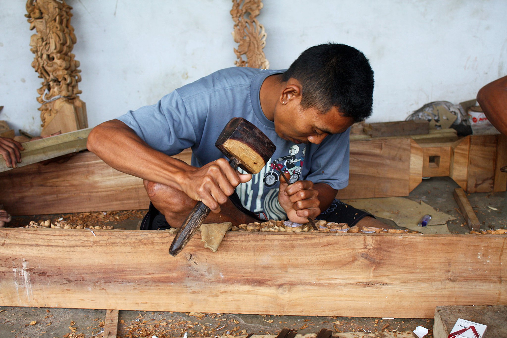 You can see how intricate the finished pieces are behind this wood worker