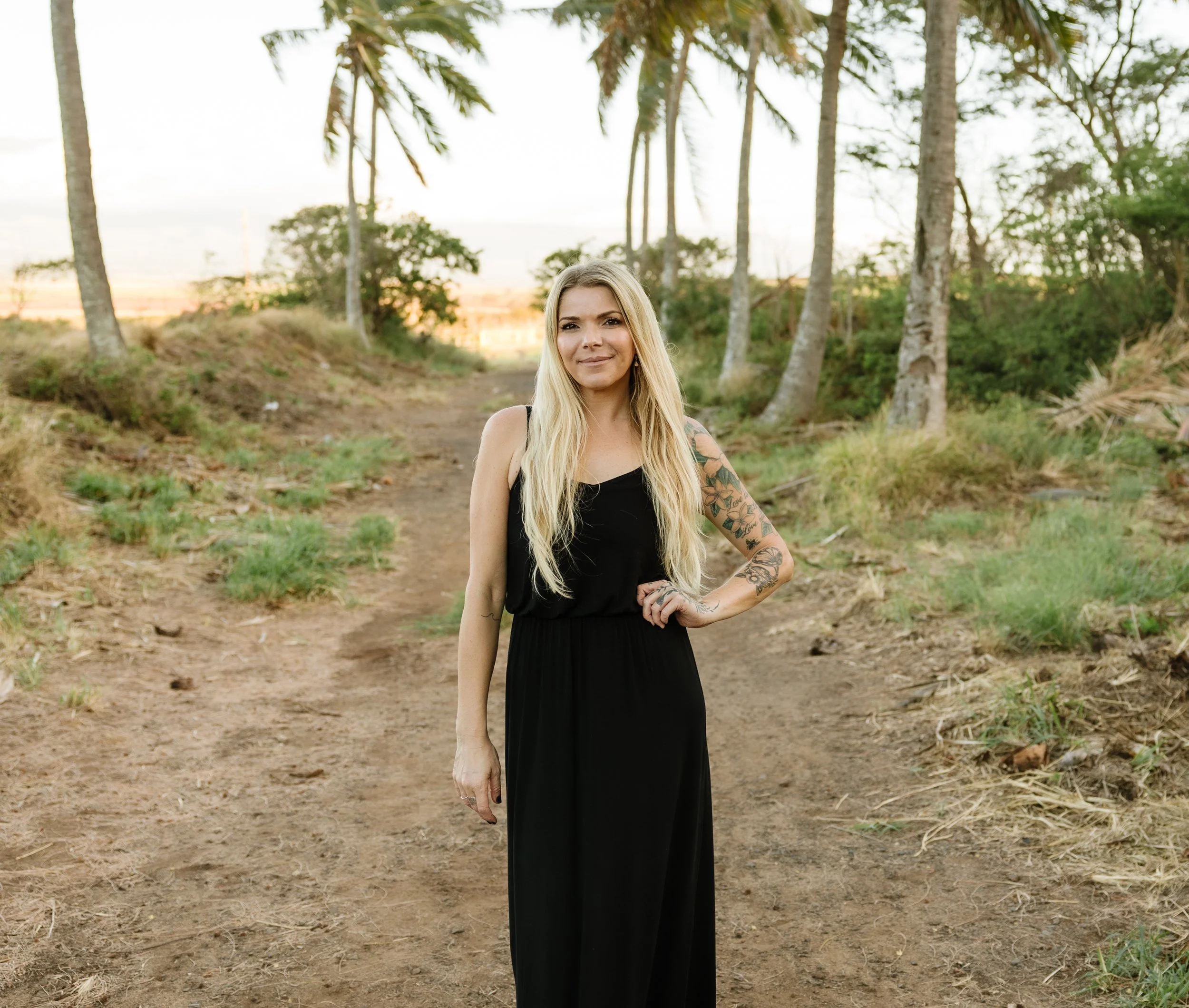 A blond woman in a black dress standing in front of the beach