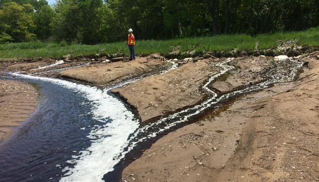 Untreated kraft pulp mill effluent flows from a broken pipe. through a wetland and into Pictou Harbour in 2014.