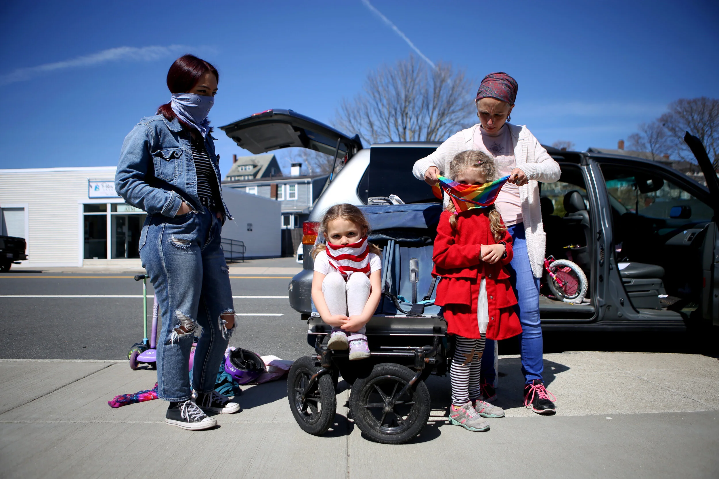 From left, Victoria Rivera, 17, Carlisle Whitfield, 5, and Ocean Whitfield, 3, wait as their mother, Tammy Whitfield, wraps a bandana around their heads before a walk on April 6 in Swampscott, MA.