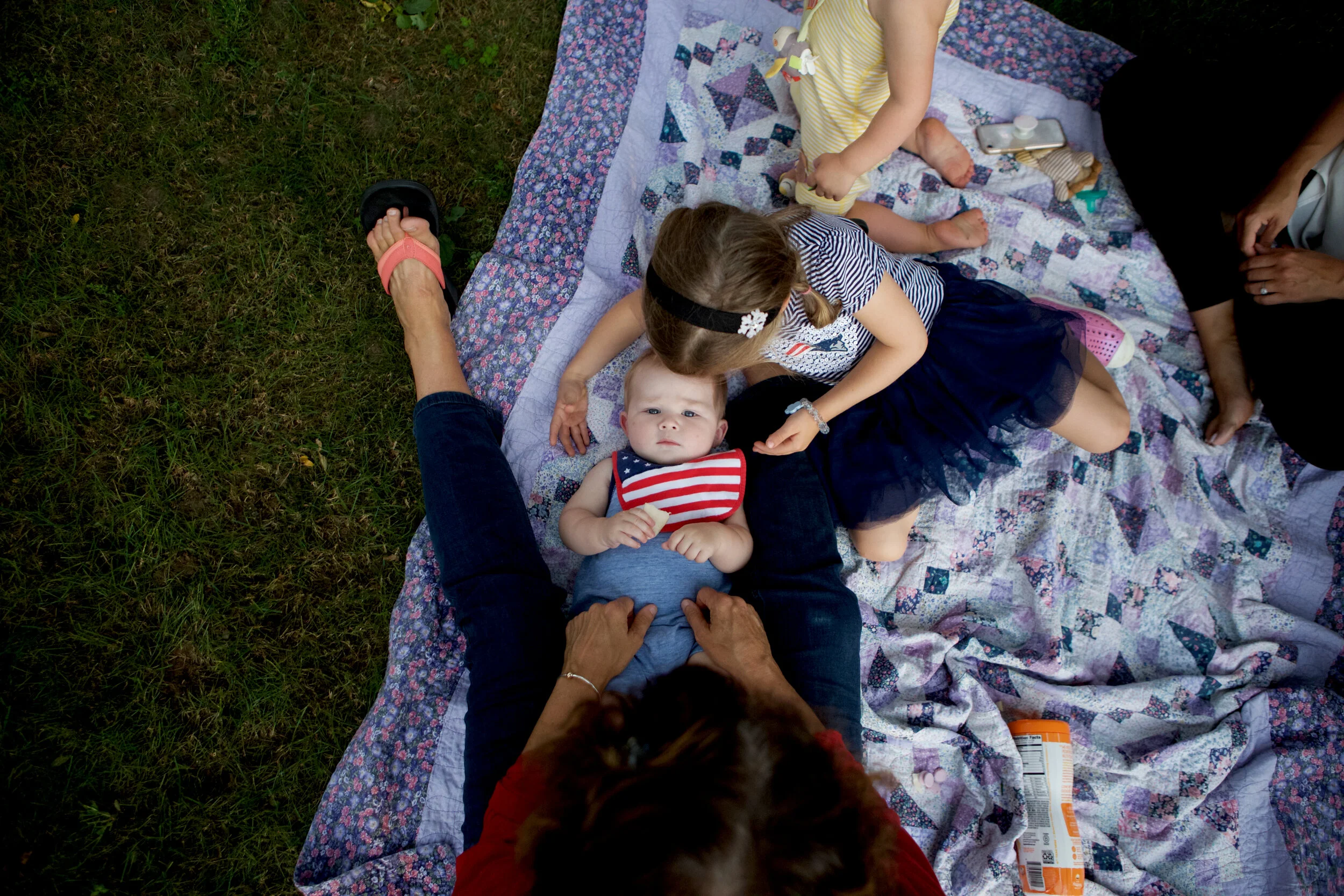 Timmy Conlon, 7 months, lies in between his grandmother, Leeann, his sisters Emily Conlon, 4, and Leah Conlon, 2, and mother Cara Conlon on a blanket during a 9/11 ceremony in Lynnfield, MA.