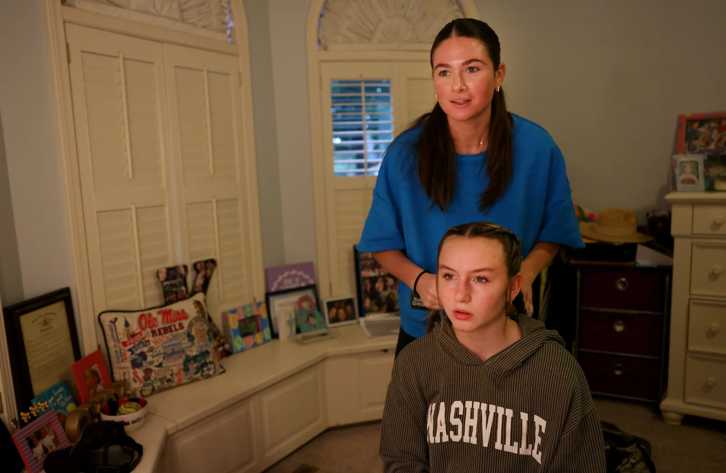 From left, Kayton Harris, Malinda Harris’s biological daughter, braids 14-year-old Alyssa’s hair in Kayton Harris’s childhood bedroom before the Delta Fair on Wednesday, Sept. 25, 2024.