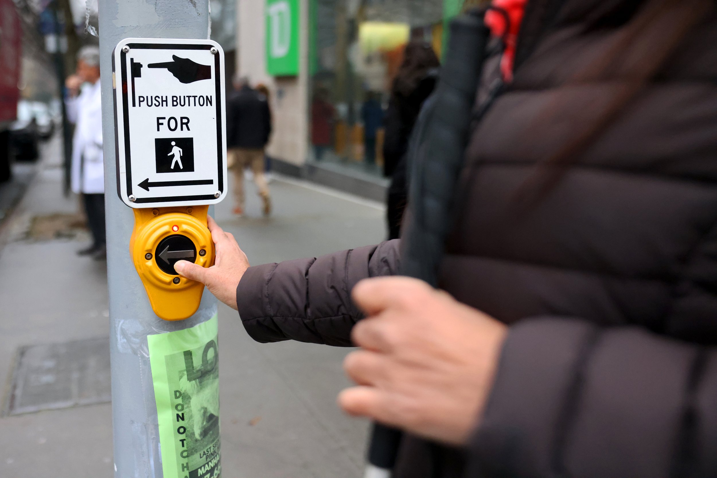 Nisha Falcigno uses an accessible pedestrian signal to cross the street on Jan. 24, 2024. An APS is used to help communicate when to cross the street in a non-visual manner.