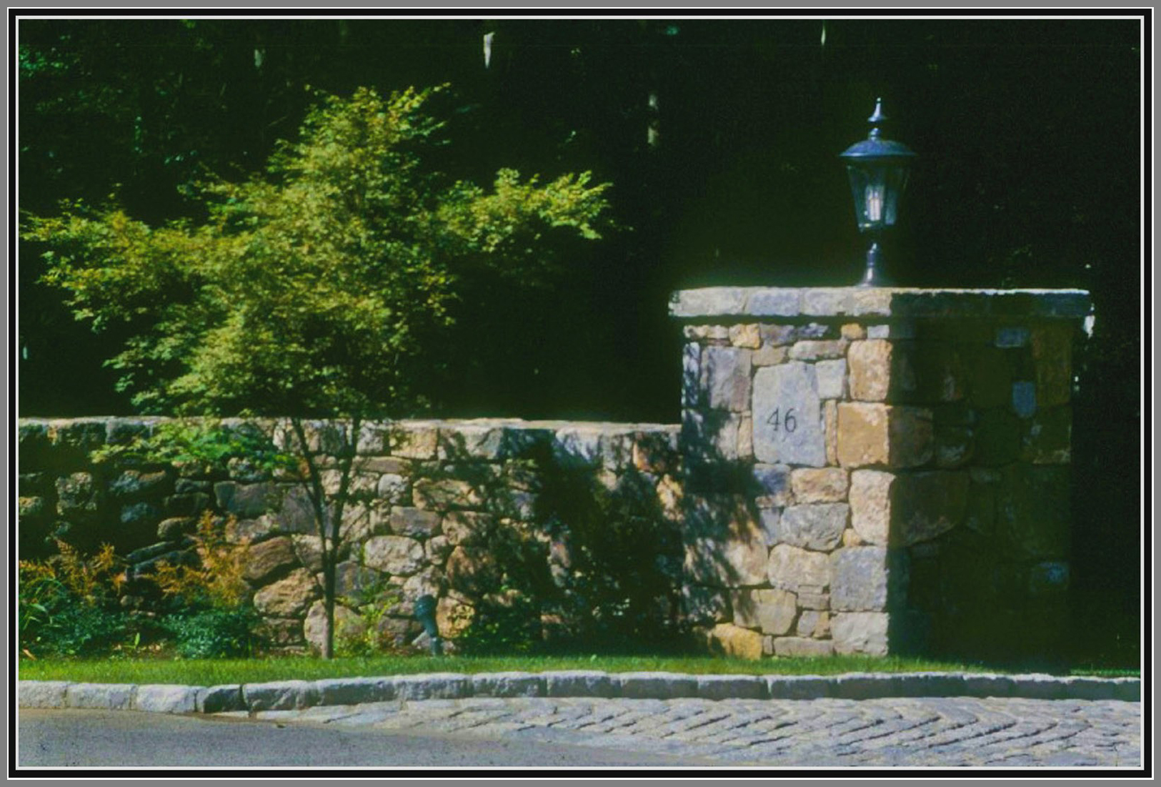 Field stone columns and wall with cobblestone apron and curb