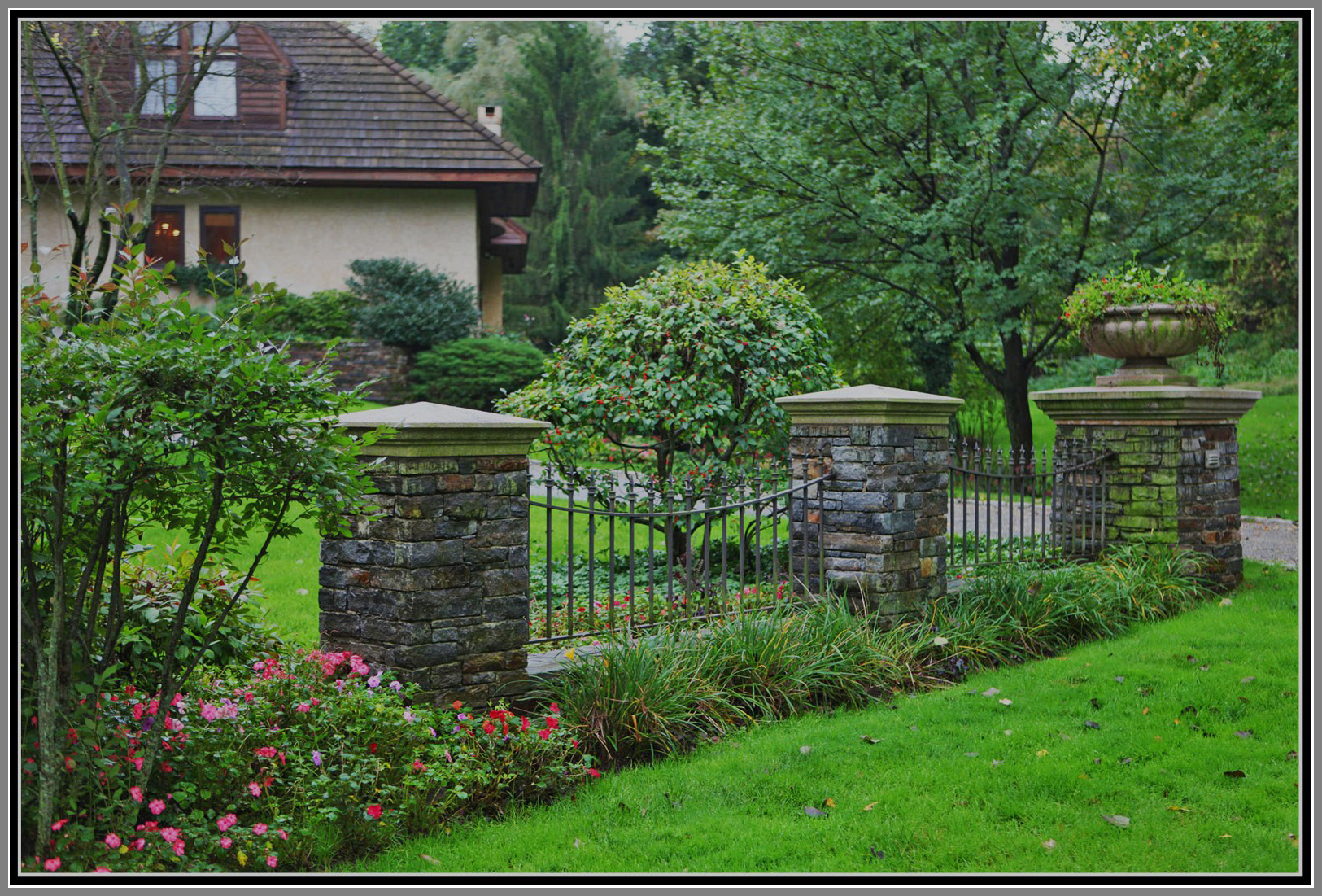 Wrought iron fence with stone column by Artistic Outdoors