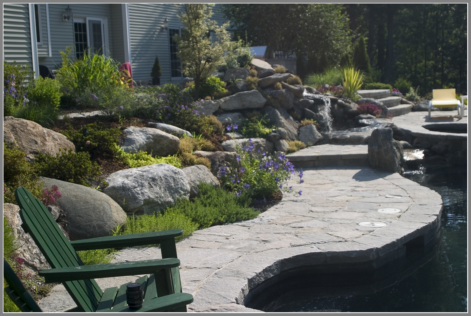 Swimming pool landscape with rock garden and stone decking
