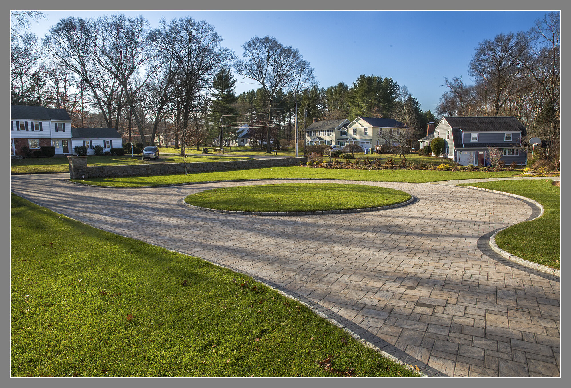 Concrete Paver circular driveway with darker border and cobble stone curb. 