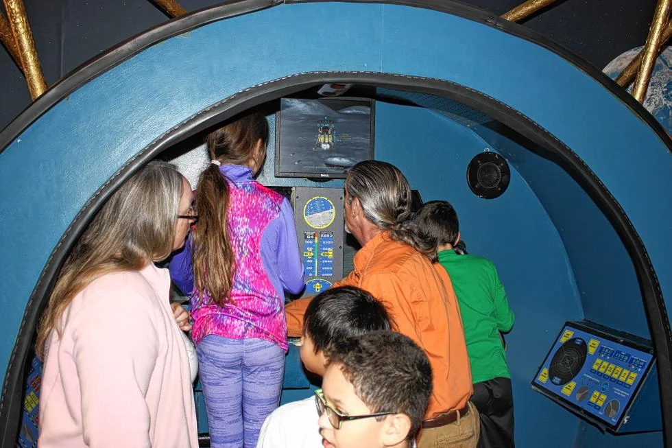 Discovery Center volunteer John Parodi (in orange) shows some Chichester Central School students the moon lander simulator. (JON BODELL / Insider staff)