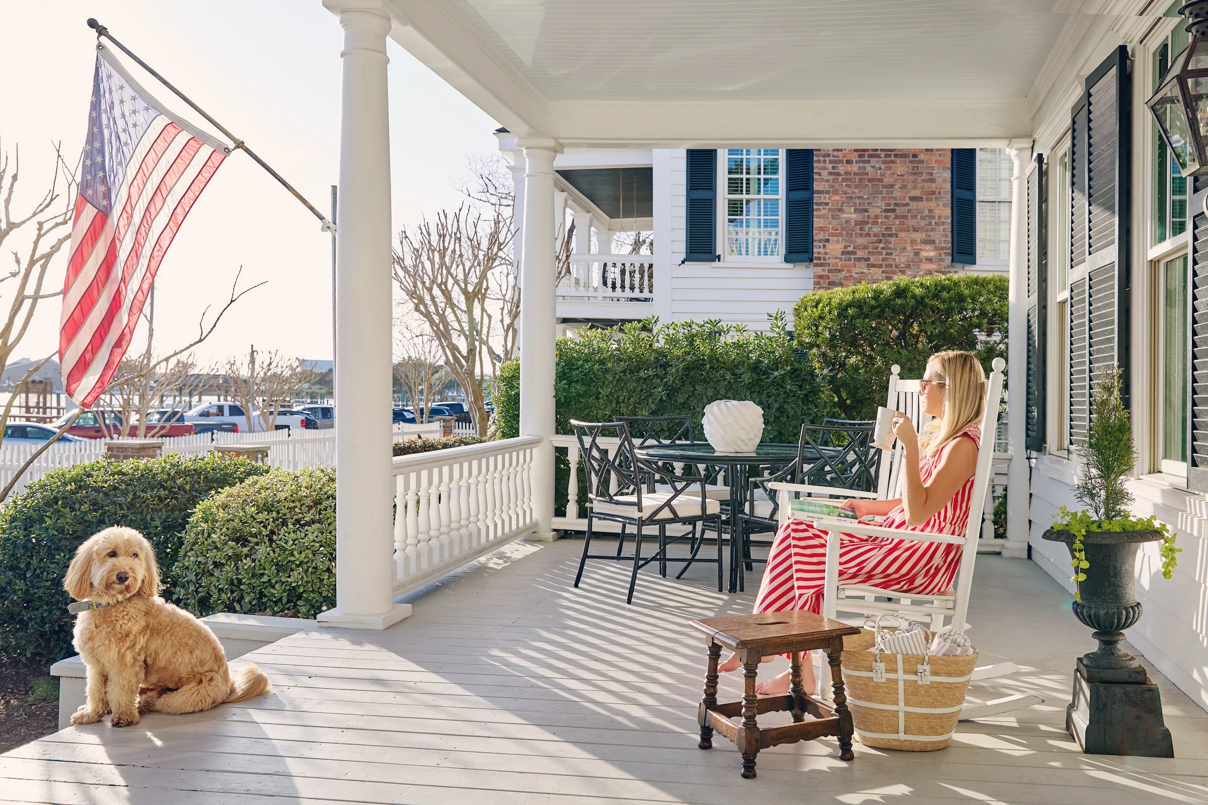 Author Kristy Woodson Harvey enjoying coffee on her front porch in Beaufort, NC. Her dog Salt sits looking out to the water. ©Stacey Van Berkel