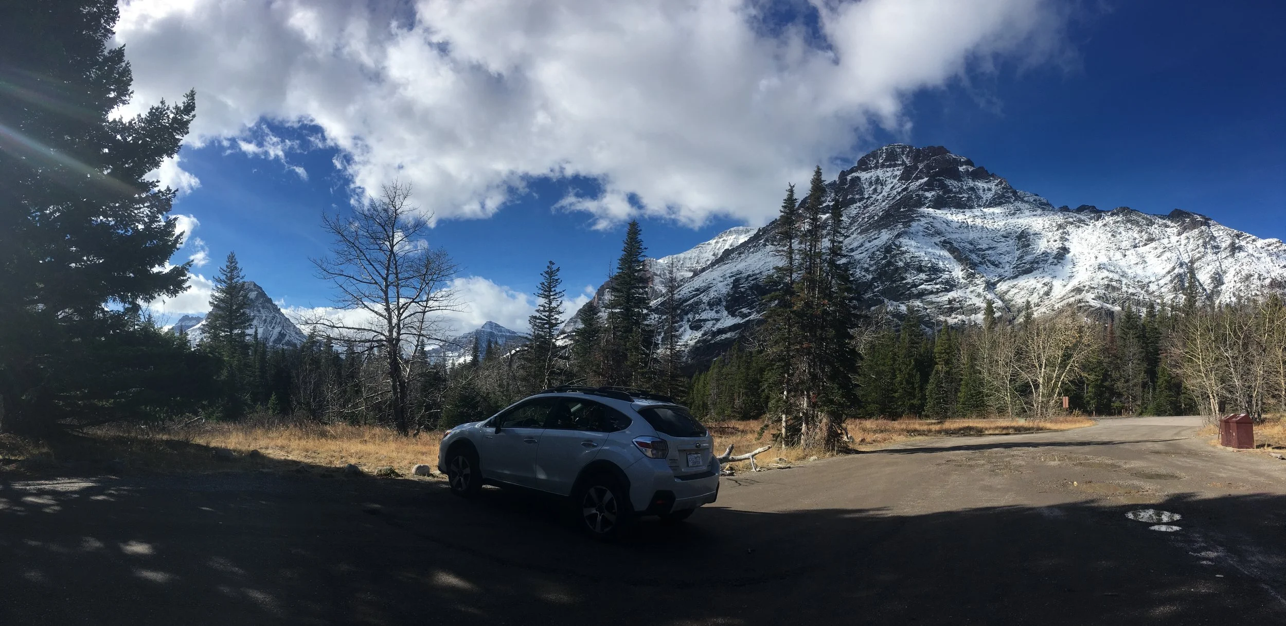 My subaru sits alone at the trailhead of a quiet glacier national park.