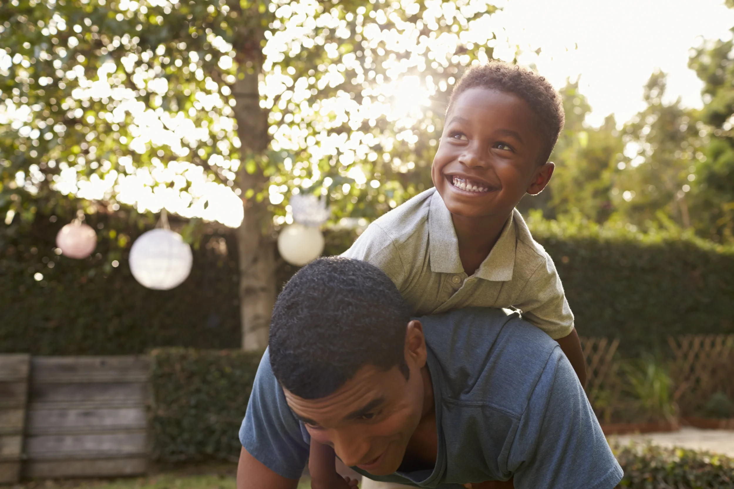 young-black-boy-playing-on-his-dad-s-back-in-a-PU7RN4X.jpg