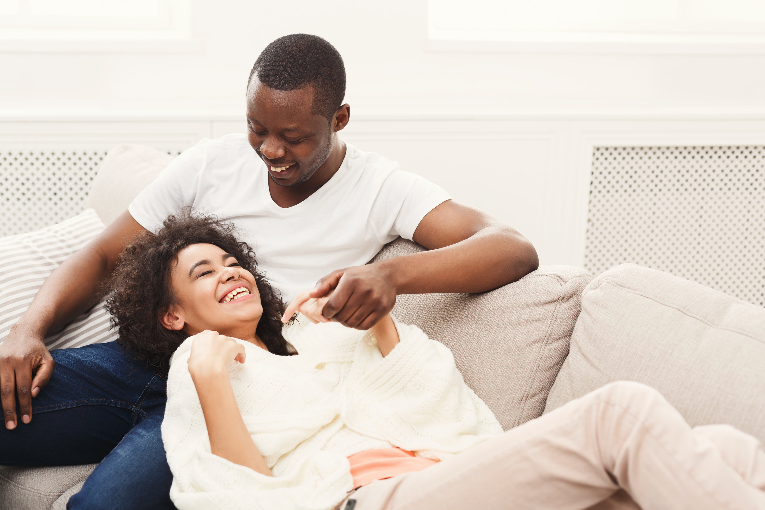 smiling-black-couple-having-rest-on-sofa-at-home-P4VA8N3.jpg