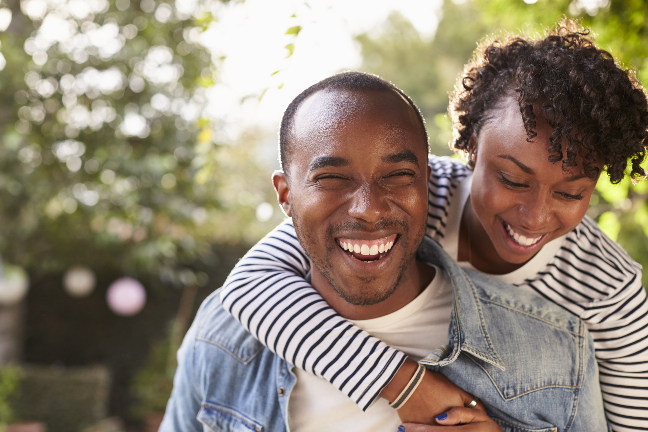 laughing-young-black-couple-piggyback-in-garden-P6YYSU6.jpg