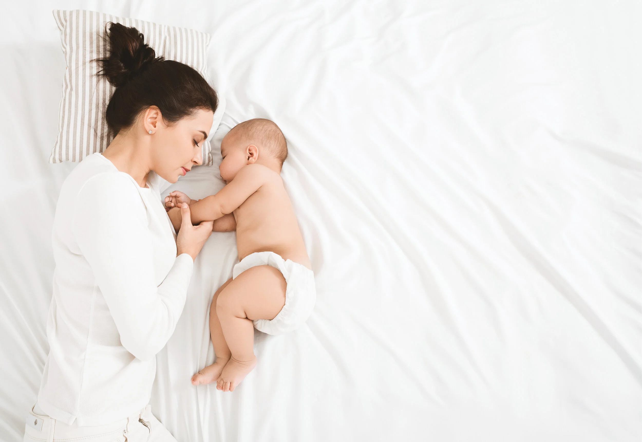 Young mom and her cute baby sleeping in bed