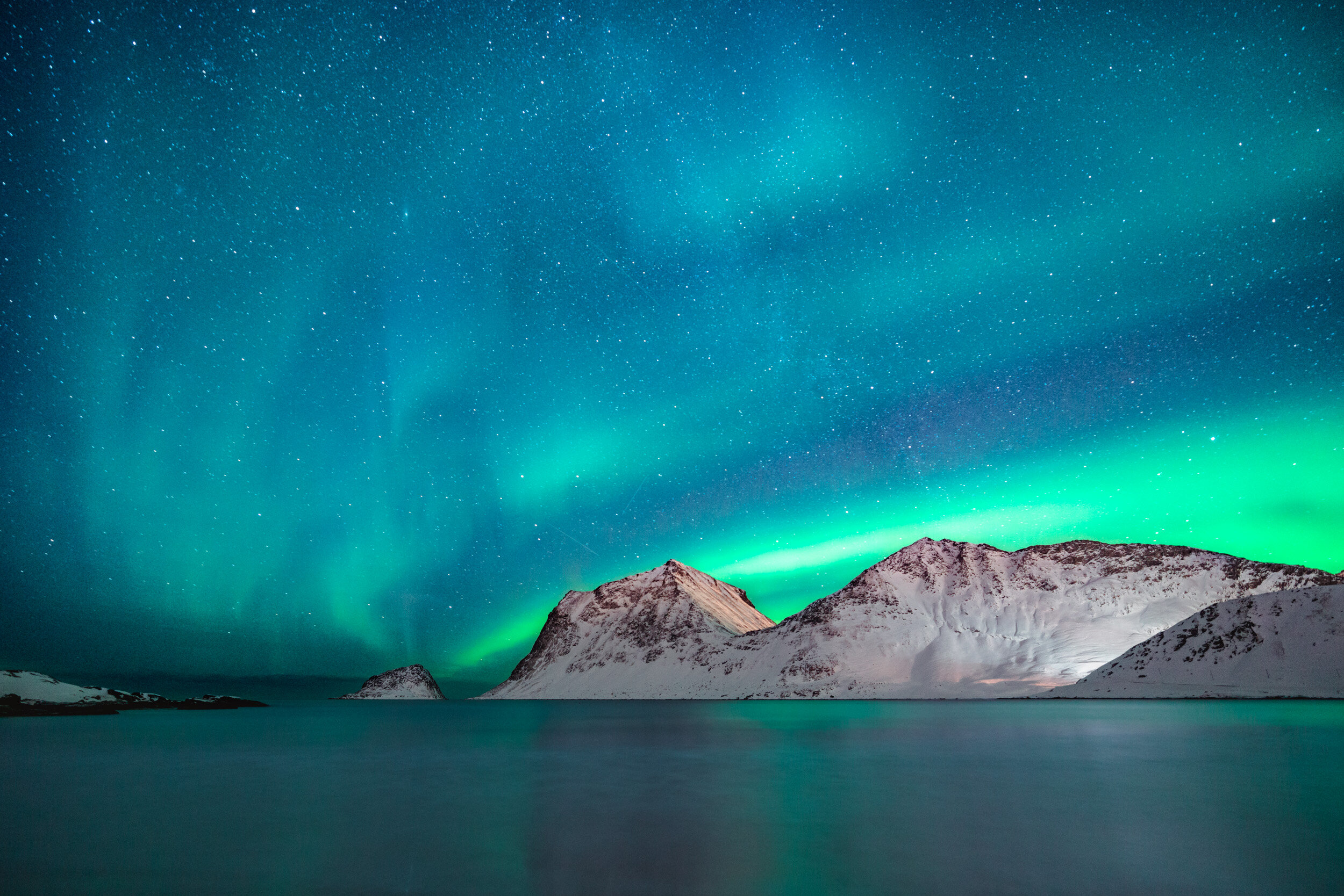 Northern Lights over snow-capped mountains at night.