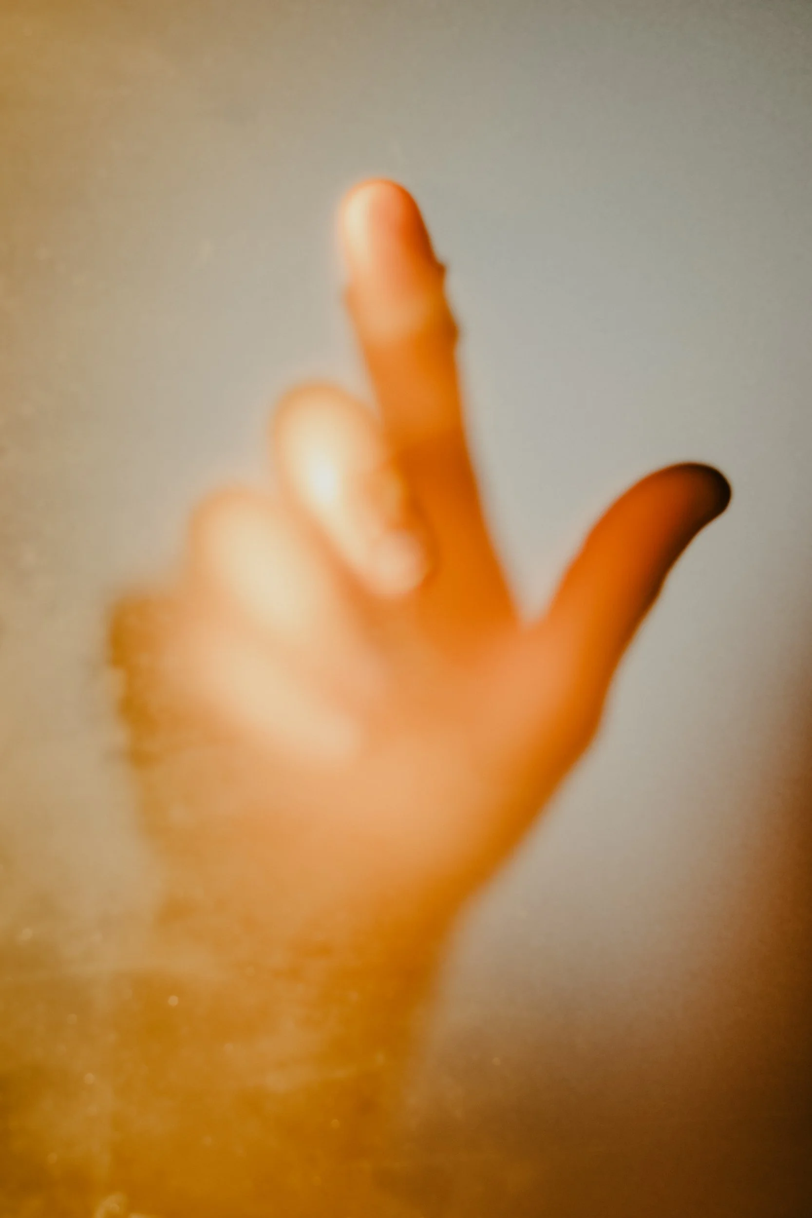 Close-up of a person's hand with index finger extended, blurred background.
