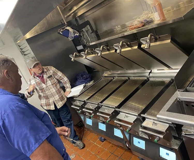 Technician training a restaurant owner how to use a new Taylor Grill