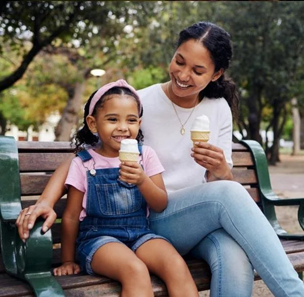 Family enjoying soft serve ice cream at a park