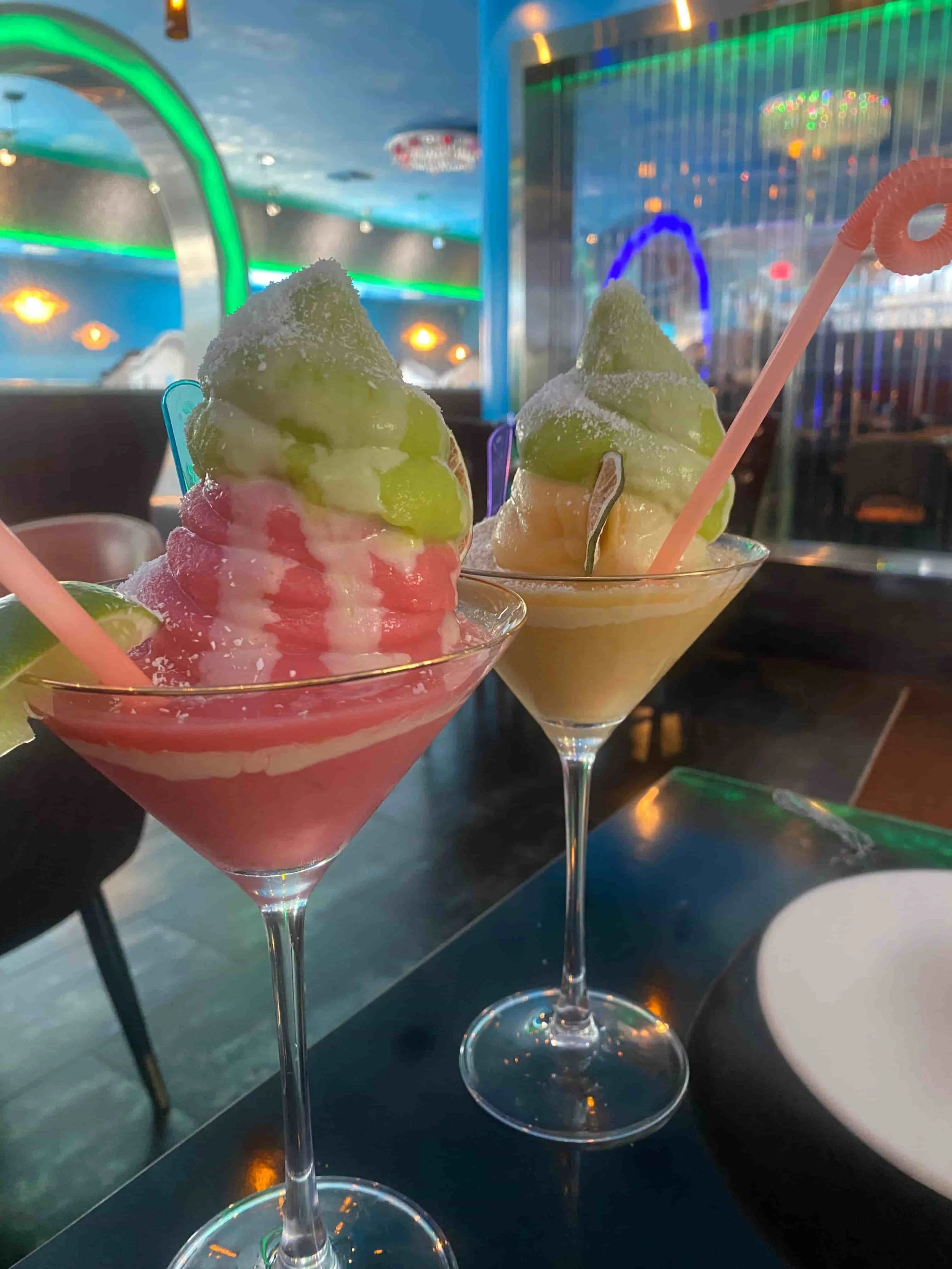 Two Soft Serve Margaritas, one strawberry margarita and one mango margarita in a glass sitting on a table