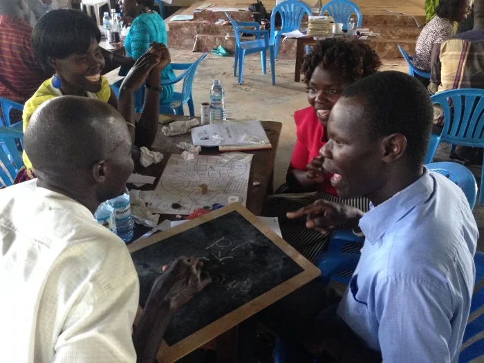 Supervisors and co-ordinators of Speed Schools in Gulu practising the 'Circle and Square' board game during a holiday training session. 