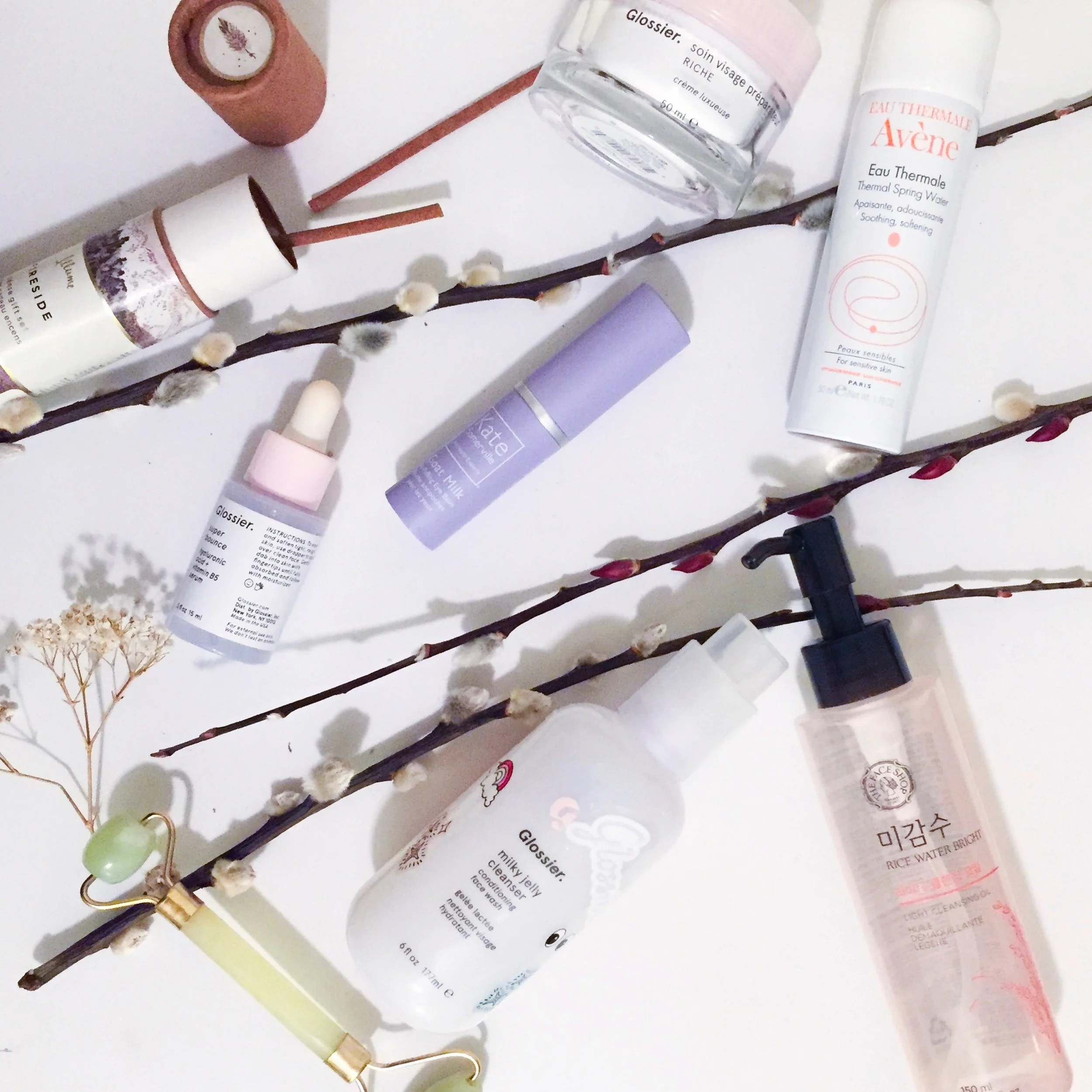 Clockwise from top: Glossier Priming Moisture Rich, Avene Eau Thermale Thermal Spring Water, The Face Shop Rice Water Bright Cleansing Oil, Glossier Milky Jelly Cleanser, a jade roller, Glossier Super Bounce, Fireside sandalwood incense, and Kate Somerville Goat Milk Eye Balm.
