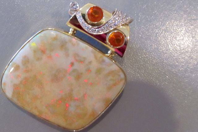   Two-sided pendant. Side A: 18k gold, bezel set Andamooka opal that has been polished front and back. Set with 2 fire opals and 2 diamonds.  