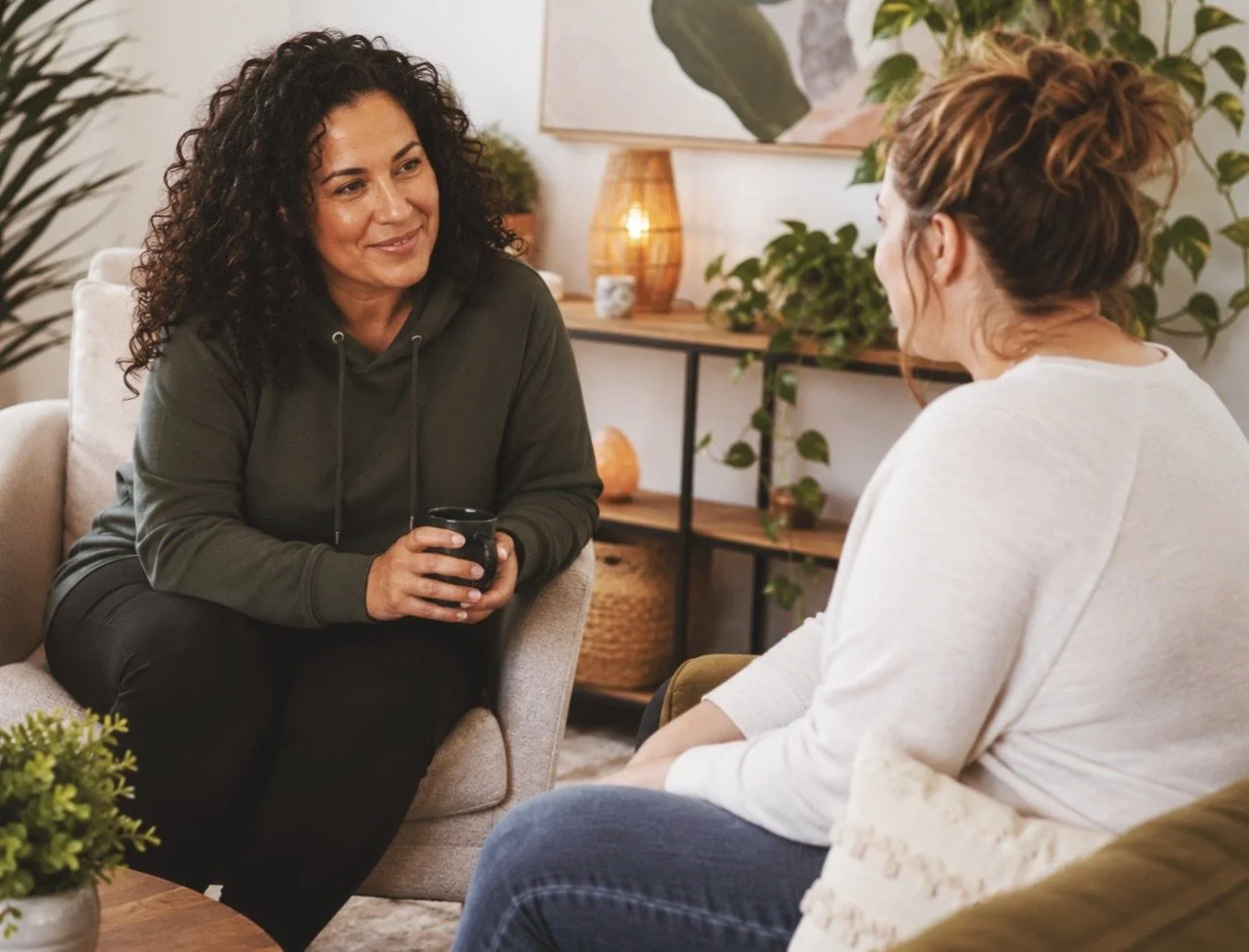Recovery coach and participant having a supportive one-on-one conversation in the At The Roots LLC office, illustrating peer recovery coaching in a welcoming environment.